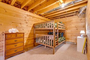 Ein Holzhütten-Zimmer mit Etagenbetten, einem Schminktisch und einer Lampe.