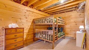 A wooden cabin room with bunk beds, a dresser, and a lamp.