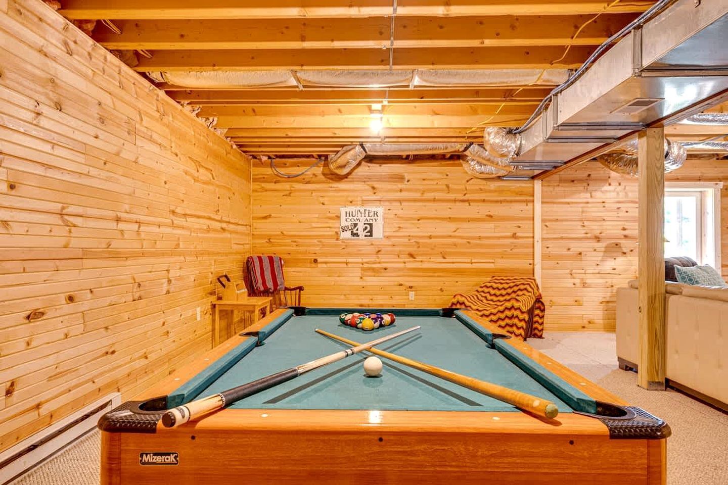 A pool table with cues and balls, a sign indicating a sold-out event, and wooden walls.