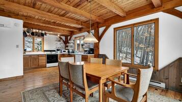 A wooden interior with a dining area, kitchen, and large windows.