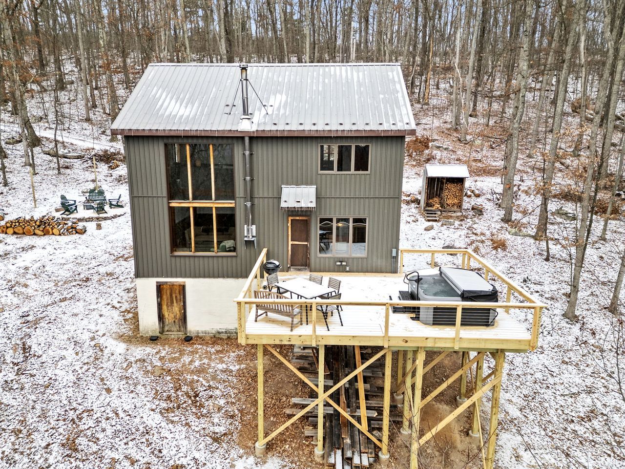 A cabin with a deck, large windows, and a chimney.