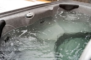 A hot tub with a control knob and a drain plug. - Charming Post-and-Beam Mountain Cabin with Hot Tub Near Berkeley Springs | Great Cacapon, WV (Great Cacapon)