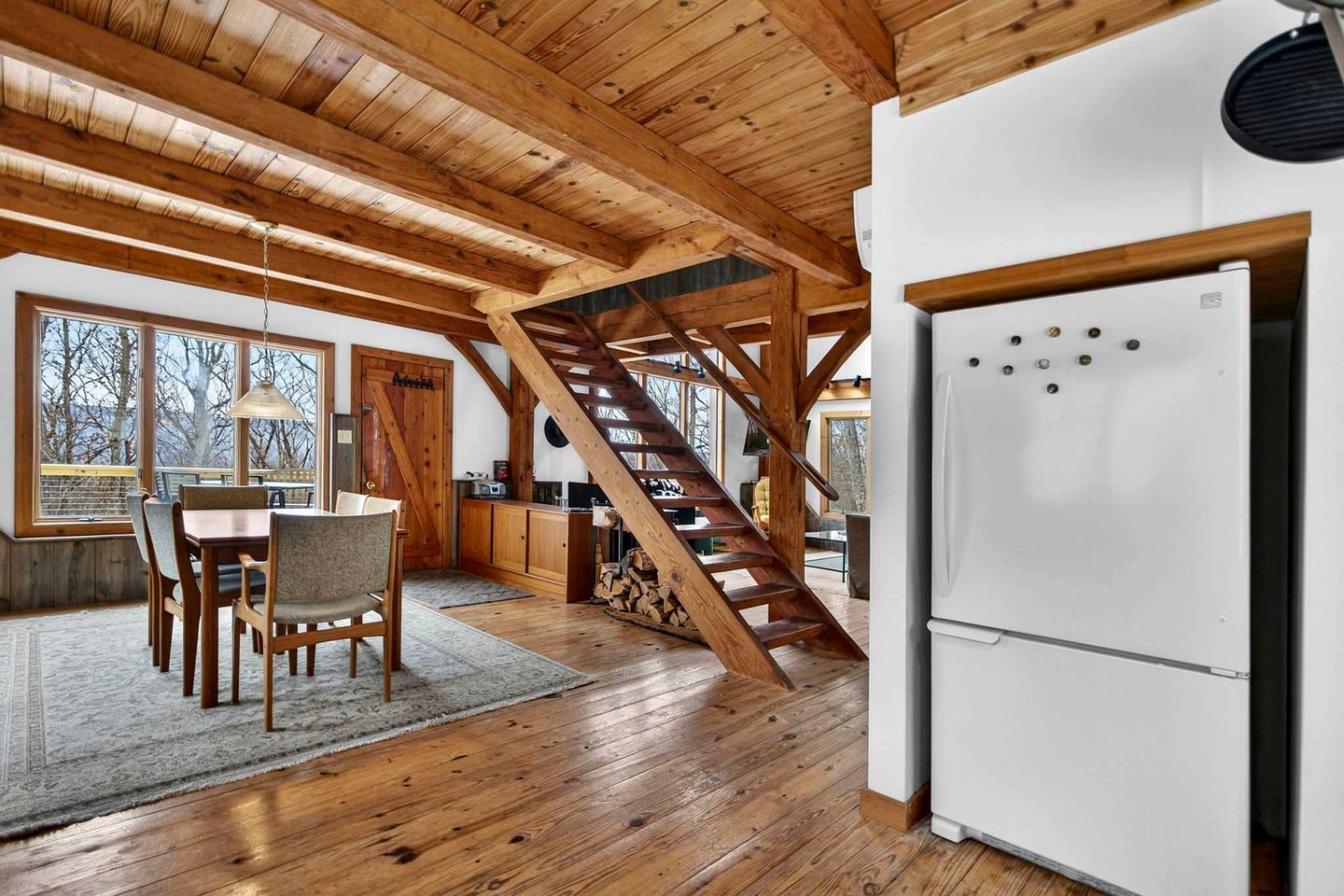 A wooden interior with a dining area, kitchen, and a staircase.