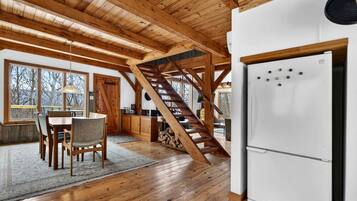 A wooden interior with a dining area, kitchen, and a staircase.