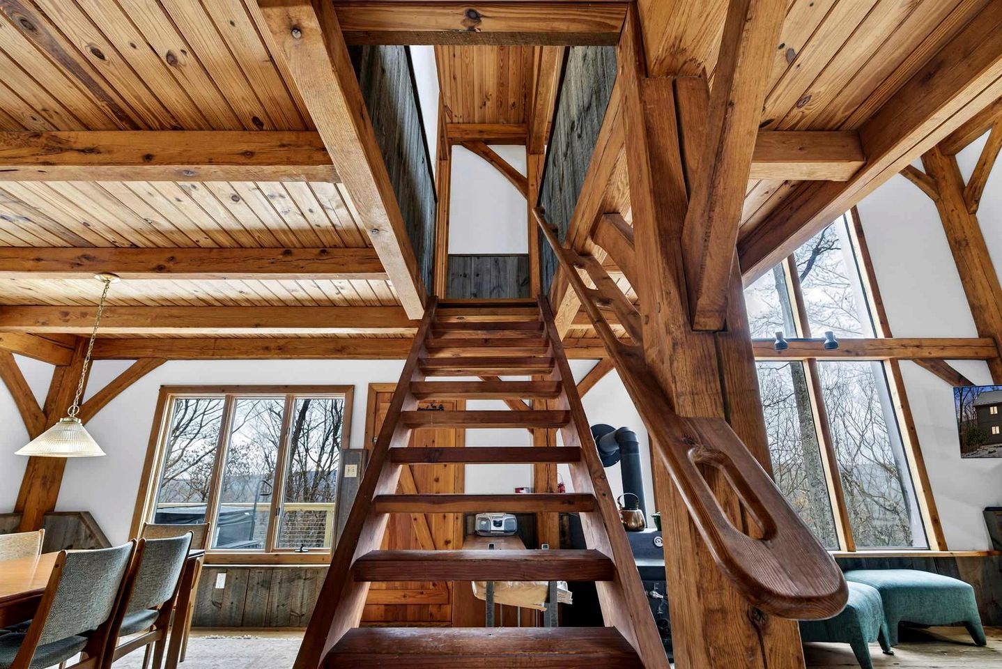 A wooden staircase leading to an upper level, with a dining area below featuring a table and chairs.