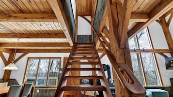 A wooden staircase leading to an upper level, with a dining area below featuring a table and chairs.