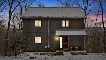 A two-story building with a metal roof, a front porch, and a visible entrance.
