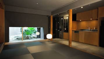 A modern interior with a kitchen, a glass door leading to a garden, and a seating area with a floor lamp.