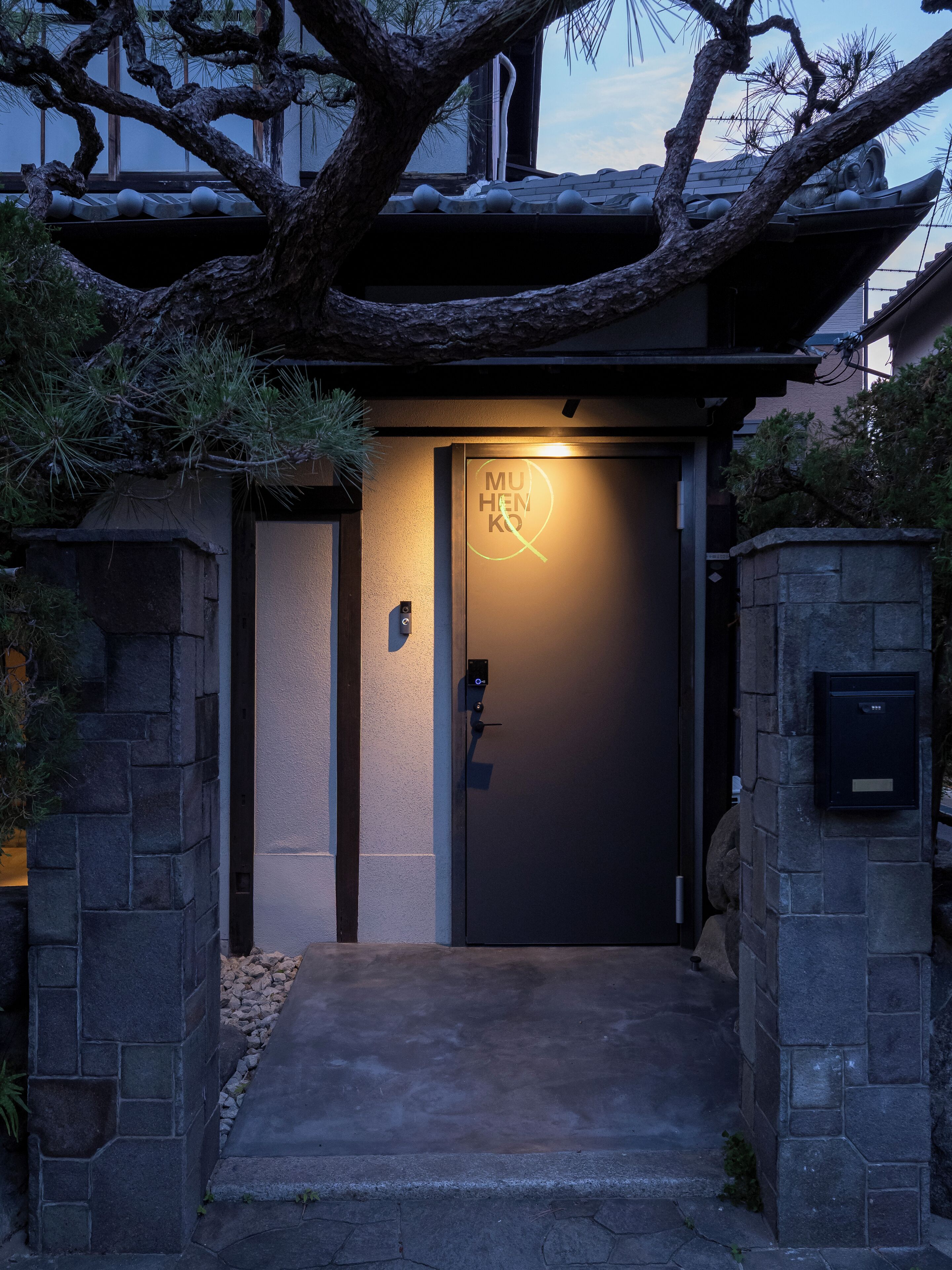 A building entrance with a dark door, stone walls, and a small step leading up to the door.