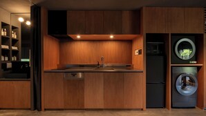 Une cuisine moderne avec des meubles en bois, un lave-vaisselle encastré et un réfrigérateur noir.