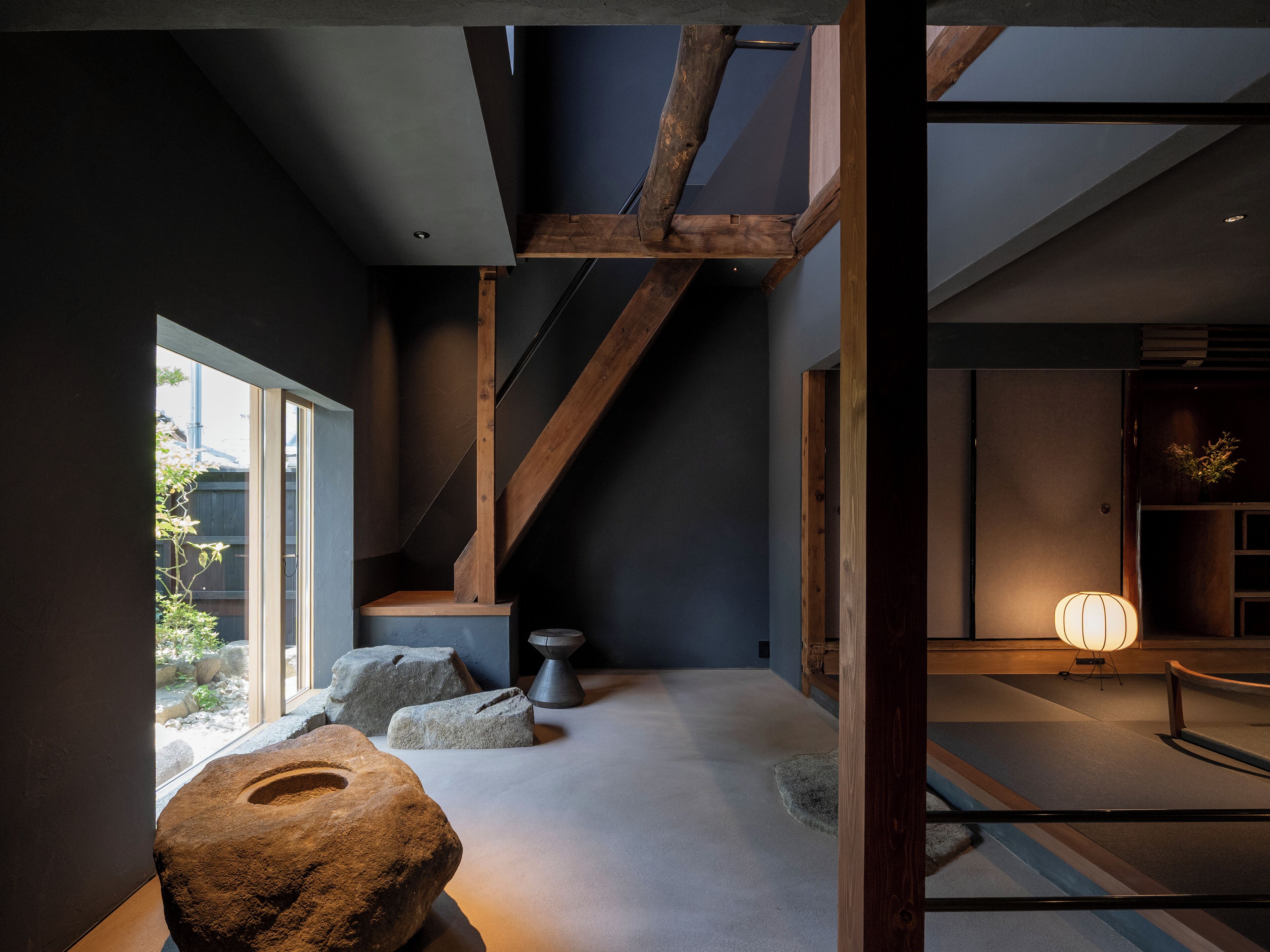 Un intérieur moderne agrémenté d’une sculpture en pierre, de poutres en bois et d’un design minimaliste.