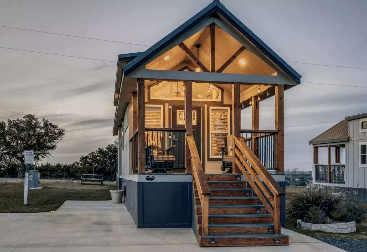 Een modern huis met een houten trap die leidt naar een overdekte veranda.