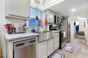 A modern kitchen with stainless steel appliances, a dishwasher, and a window with blinds. - Relaxing Tiny Home Retreat with Resort Amenities Near Fredericksburg, TX (Fredericksburg)
