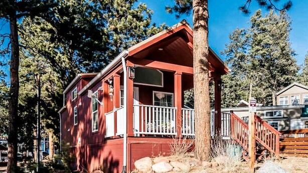 A red cabin with a porch, surrounded by pine trees and rocks. - Quaint Tiny House in Woodland Park, Colorado near Garden of the Gods (Woodland Park)