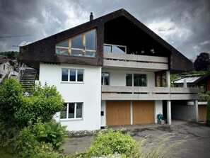 Ein zweistöckiges Gebäude mit geneigtem Dach, großen Fenstern und einer Garage.