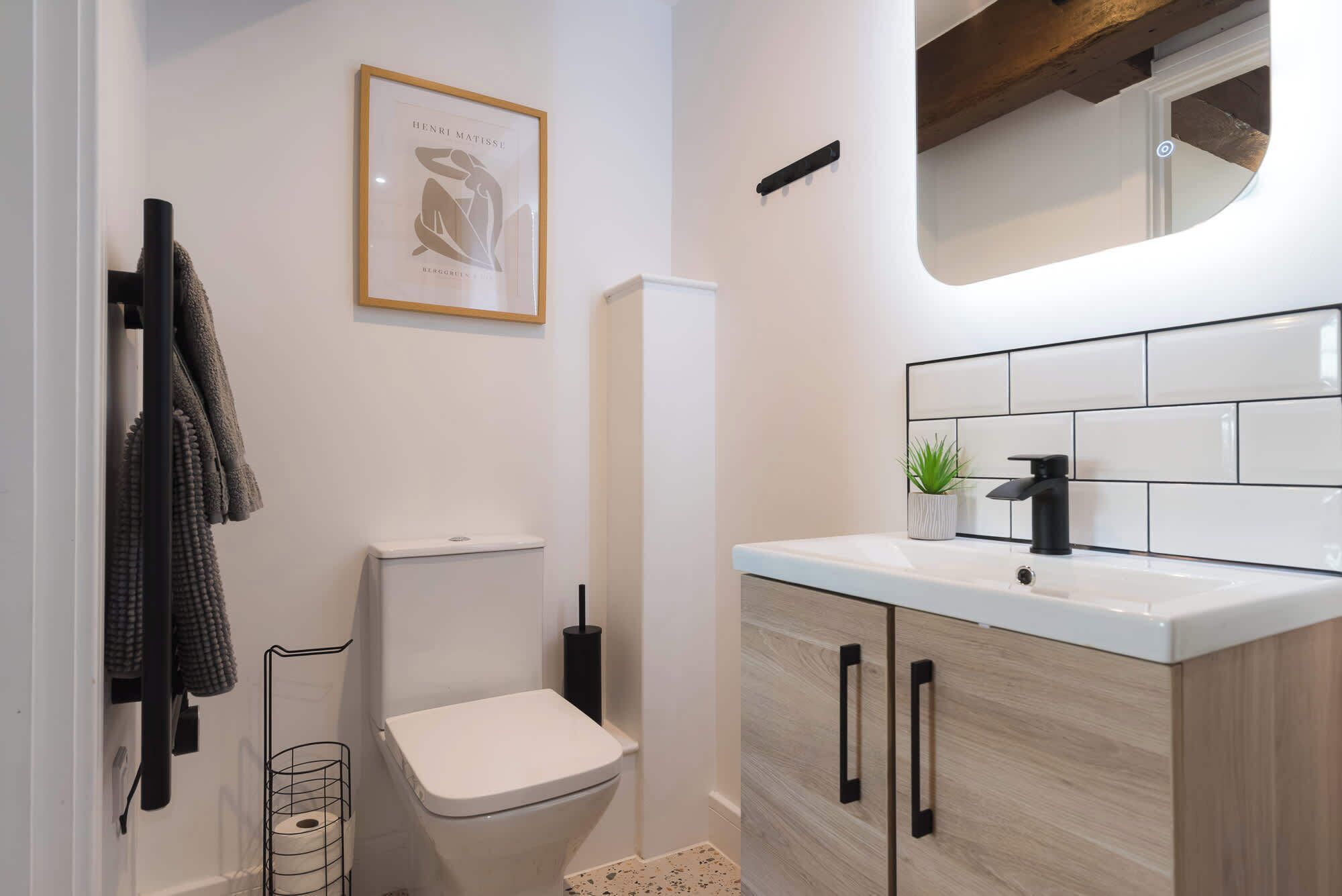 Et moderne badeværelse med toilet, vask og et billede i ramme på væggen.