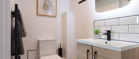 Et moderne badeværelse med toilet, vask og et billede i ramme på væggen.