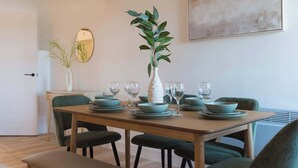 A dining area with a wooden table set for six, surrounded by green upholstered chairs. - Stunning 3-bed Home in Newark by Renzo, Free Parking, Hotel Alternative (Newark-on-Trent)