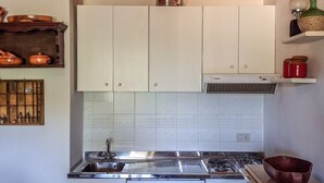Cocina con gabinetes blancos, estufa de acero inoxidable y salpicadero de azulejos.
