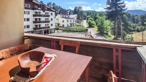 Un balcón con mesa y sillas de madera, con vistas a una zona residencial con casas y árboles.