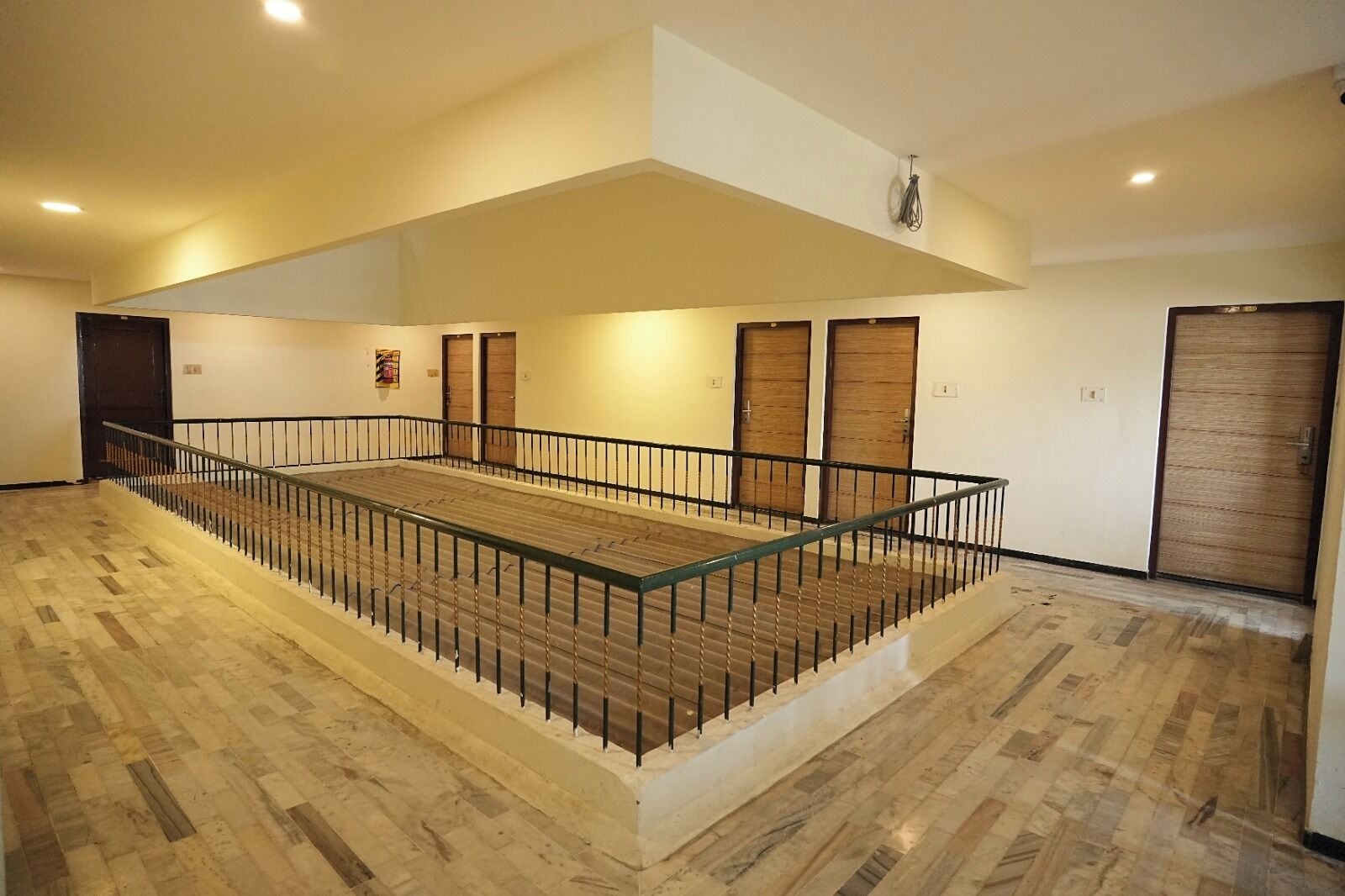 Zona interior espaiosa amb sòl de fusta, barana de vidre i diverses portes.