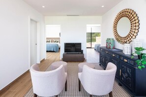 A modern living room with a sofa, two armchairs, a TV, and a decorative mirror. - Paraiso Azul (Faro)
