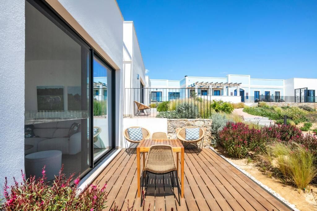 Un bâtiment moderne doté d’une terrasse en bois, d’un espace salon extérieur et d’un jardin.
