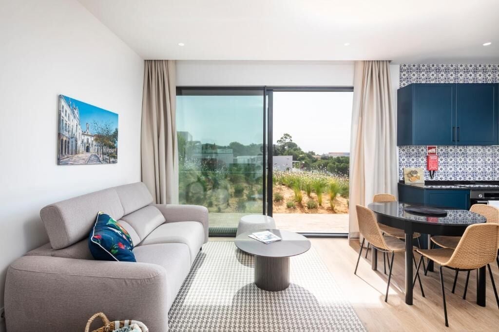 Un salon moderne comprenant un canapé, une table basse ronde et un coin repas avec des chaises et une table.
