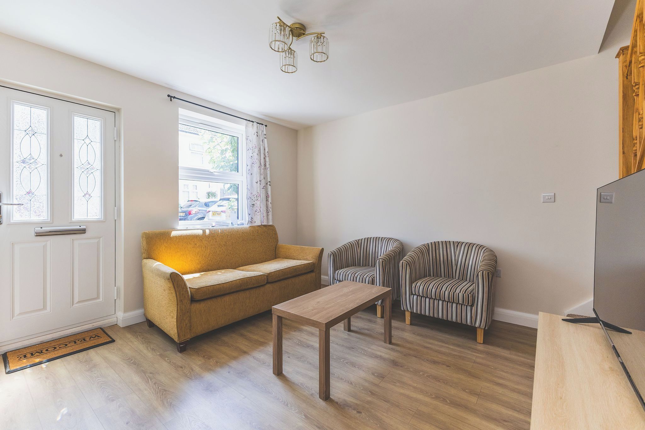 A compact living space with a sofa, two striped chairs, a coffee table, and a door with frosted glass panels.