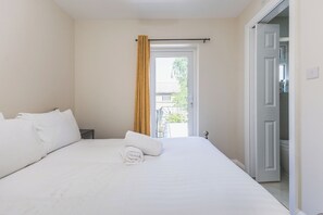 Een hotelkamer met een bed, een raam met gordijnen, een deur en uitzicht op buiten.