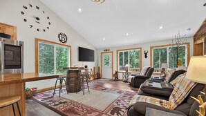 Ein geräumiges Wohnzimmer mit großem Fenster, Kamin, einer Couch und einem Fernseher.