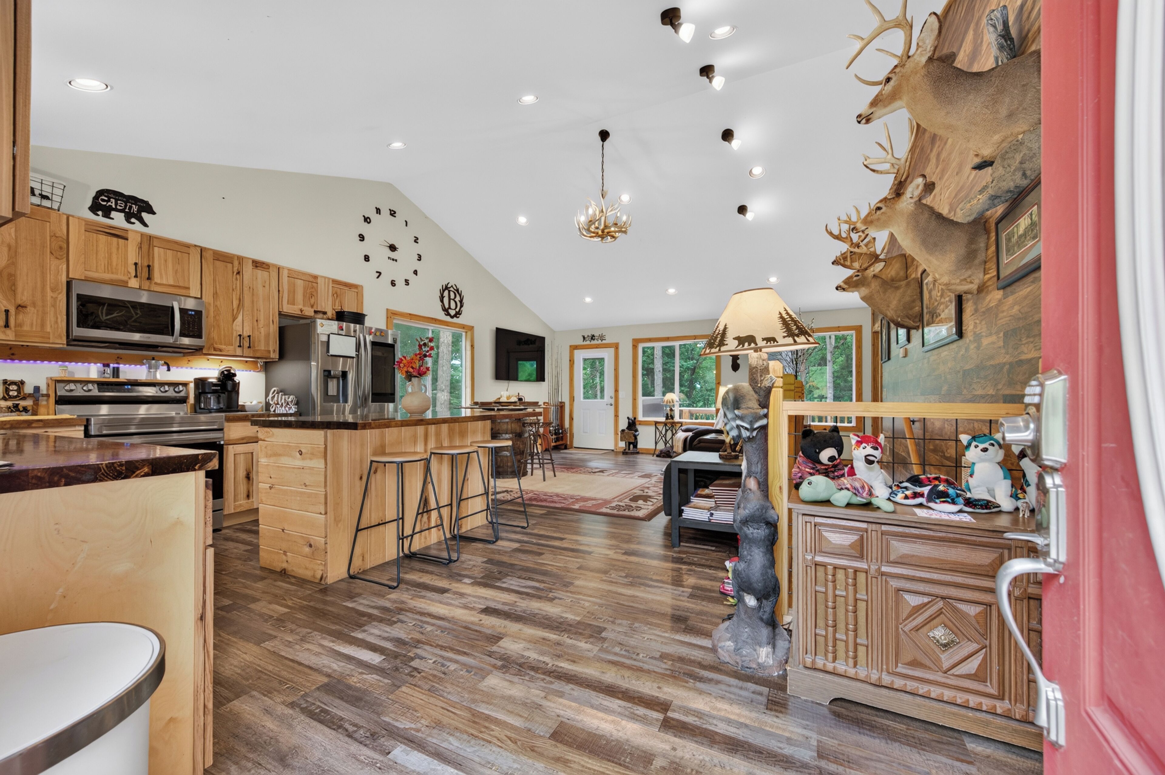 An open-concept living space and kitchen with wood flooring, rustic cabinetry.