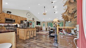Eine geräumige Küche mit Holzausstattung, einer zentralen Kochinsel und einem Essbereich mit einer Kronleuchter.