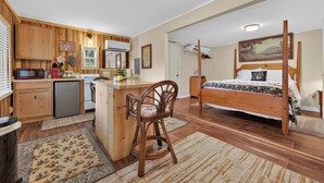 A bedroom with a four-poster bed, a wooden desk, and a kitchenette. - Cozy lakeside cabin with peaceful views, a covered porch, fire pit, and private rural getaway. (Galax)