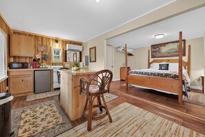 A bedroom with a four-poster bed, a wooden desk, and a kitchenette. - Cozy lakeside cabin with peaceful views, a covered porch, fire pit, and private rural getaway. (Galax)