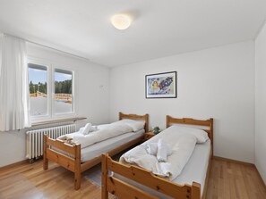 A room with two wooden beds, a radiator, a window with curtains, and a framed picture on the wall. - Nr.05 Haus Sursilvana Appartement/Fewo,   Nr.05 Haus Sursilvana by Interhome (Lenzerheide)
