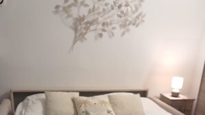 A neatly made bed with a white and beige bedspread, two pillows, and a nightstand with a lamp. - L'Eden - Unique and Charming - Suquet (Cannes)
