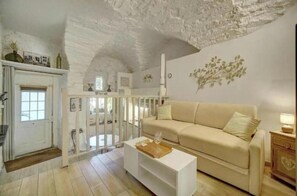Ein Wohnzimmer mit hohen Decken, einem beigen Sofa, einem weißen Couchtisch und einem weißen Schrank.