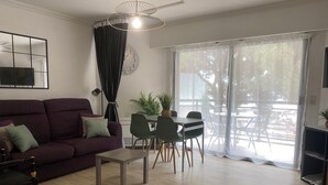 Een moderne woonkamer met een bank, salontafel, eethoek met stoelen en een groot raam met uitzicht.