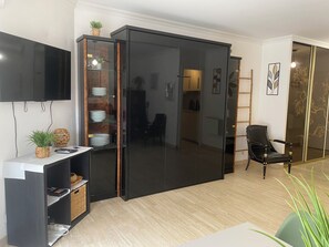 Ein modernes Wohnzimmer mit Schiebeglastüren, einem an der Wand montierten Flachbildfernseher und einem schwarzen Ledersessel.