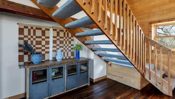 A wooden staircase with blue carpeted steps, a checkered wall, and a wooden console table with decorative items.