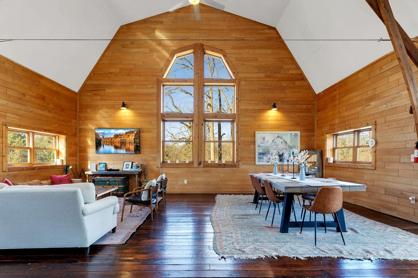 A log cabin interior with a dining area, a sofa, and artwork on the walls.