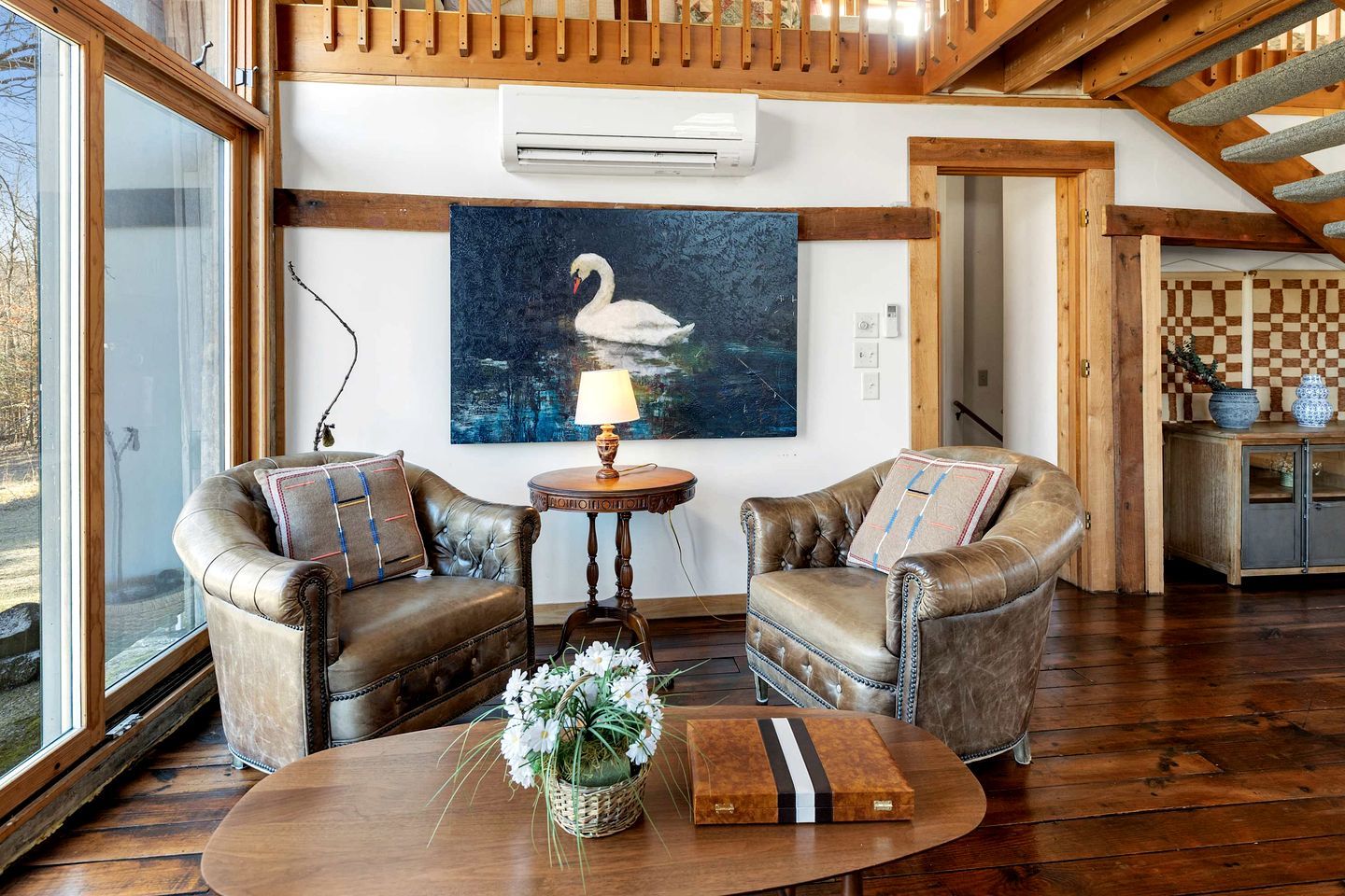Una habitación con dos sillones de cuero, una mesa de centro de madera, un cuadro de un cisne y una pared a cuadros.