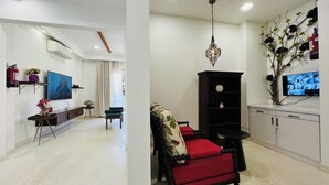 Una sala de estar moderna con un sofá, un televisor, una estantería y una planta decorativa.