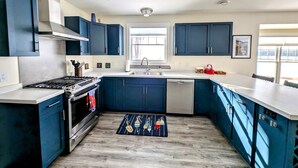 Una cucina moderna con mobili blu scuro, un piano cottura in acciaio inossidabile e una finestra sopra il lavello.