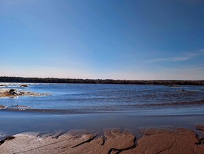 A beach with clear water, a distant shoreline, and a clear sky. - Stunning Waterfront Beach House with Private Beach and Fire Pits near Bar Harbor, Ellsworth Maine (Ellsworth)
