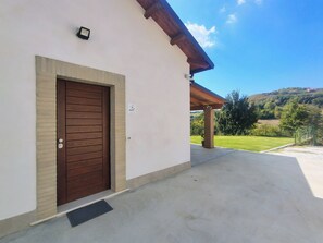 A building with a brown door, a small sign above the door, and a covered outdoor area with a view of a green landscape. - FRANK'S COTTAGE - COUNTRY HOUSE: VILLA FOR EXCLUSIVE USE (Abruzzo)