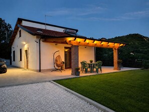 A house with a covered patio, a hanging chair, and a table with chairs.