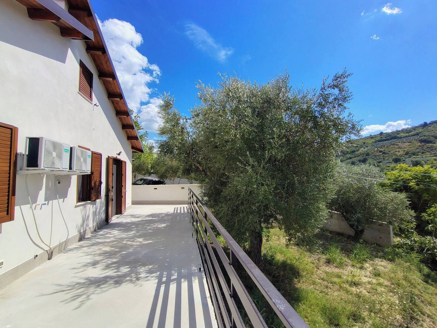 Un edificio con un balcone, condizionatori d'aria a vista e vista su una collina.