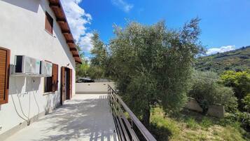 Un edificio con un balcone, condizionatori d'aria a vista e vista su una collina.